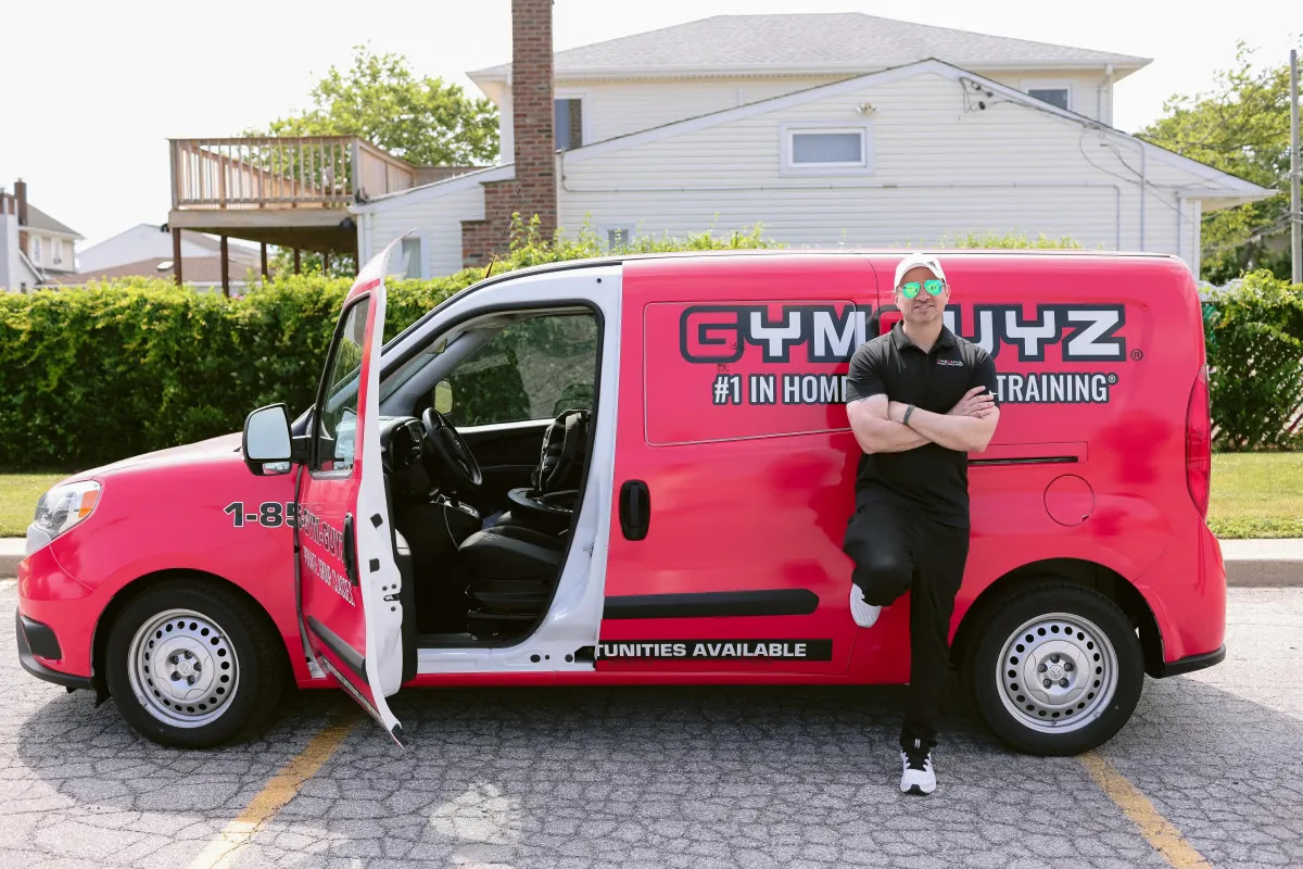 A certified adaptive fitness trainer assisting a client with special needs in a workout session at GymGuyz North Queens.