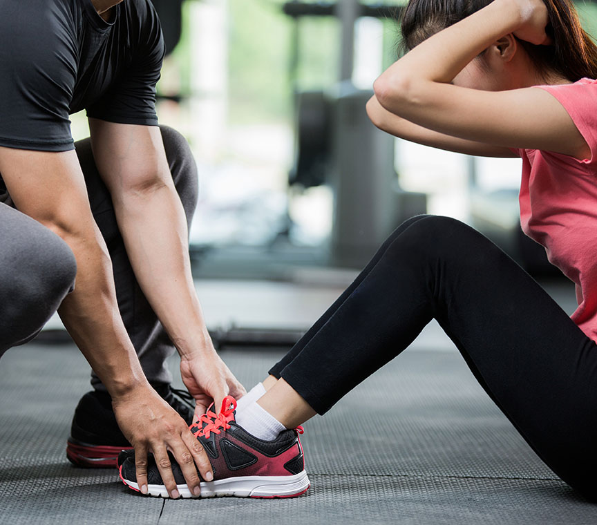 A certified adaptive fitness trainer assisting a client with special needs in a workout session at GymGuyz North Queens.