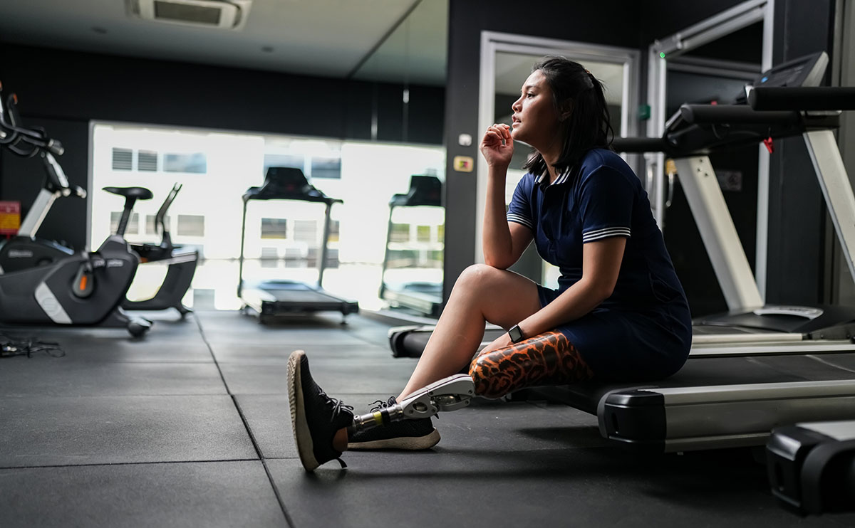 A certified adaptive fitness trainer assisting a client with special needs in a workout session at GymGuyz North Queens.